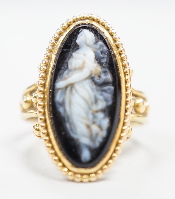 An early 20th century yellow metal and black sardonyx set cameo ring, carved with the figure of a classical lady, size G/H, gross weight 3.3 grams